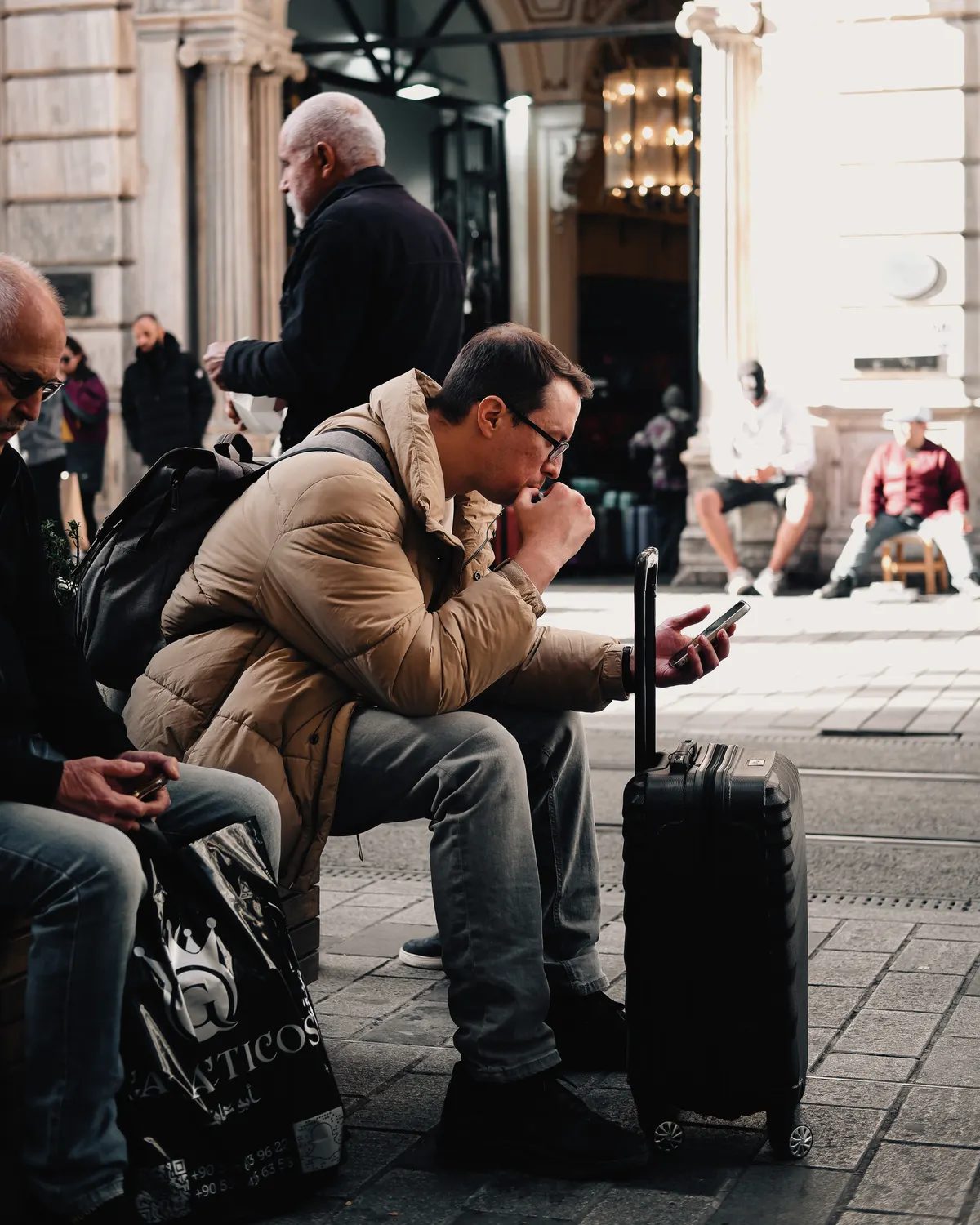 Traveler with a suitcase checking his phone in an unfamiliar city